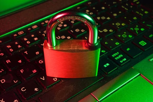 Padlock resting on a laptop keyboard lit in red and green, representing cybersecurity