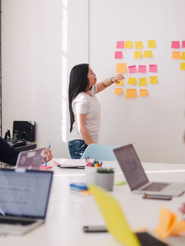 Team member arranging colorful sticky notes on a whiteboard during a planning meeting